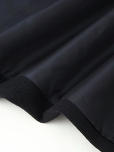 Gros plan de l'ourlet du manteau montrant la doublure en polyester et la texture en laine