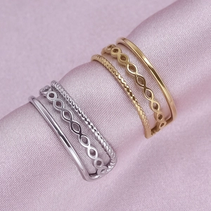 Detailed macro view of gold and silver layered rings with infinity symbol on pink satin