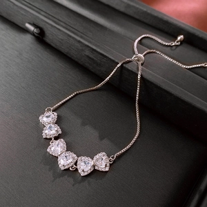 Detail of adjustable silver heart bracelet with six cubic zirconia stones on black box