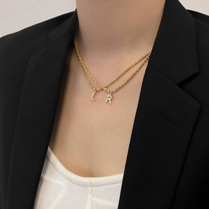 Détail du collier double couche en titane doré avec pendentifs lettres L et R en zircon
