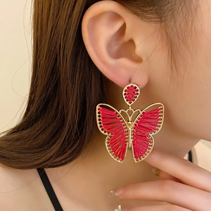 Close-up of bohemian butterfly earrings with magenta woven thread on model's side profile