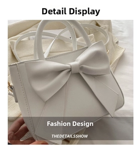 Detailed view of white leather handbag with a large bow design and polished metal hardware