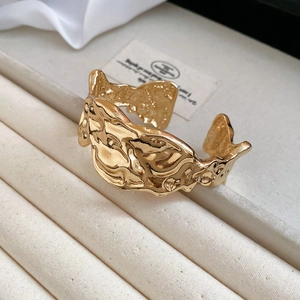 Detailed view of wide gold cuff bracelet featuring artistic molten lava texture on display