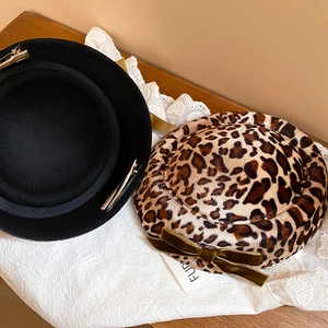 Close-up of leopard print fabric hair clip with a dark green velvet bow and metal duckbill clip