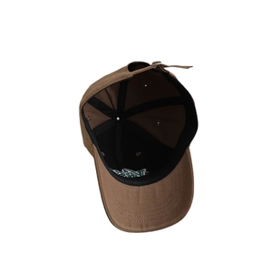 Inside view of brown cotton baseball cap showing black sweatband and adjustable metal buckle