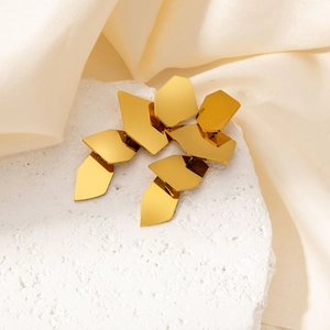 Macro detail of layered irregular gold geometric pendants on white textured stone background