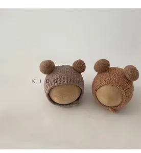 Detail of knit baby earflap hats with dual pom-poms on wooden mannequin heads