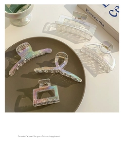 Close-up of iridescent acrylic shark hair clips in various geometric shapes on tray