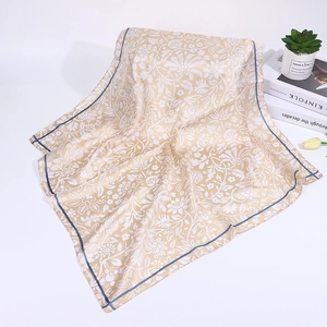 Detail of square silk scarf featuring cream paisley floral patterns and gray striped edges