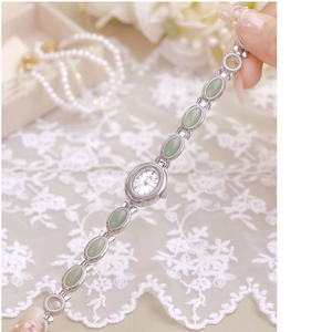 Elegant vintage style women's silver watch with green stone link bracelet on lace cloth