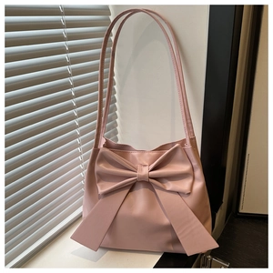 Pink shoulder bag featuring a large bow detail on a sunny windowsill background
