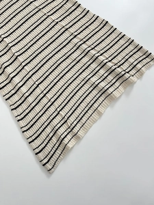 Makrodetail der Textur eines hochwertigen gestreiften Strickkleides in Creme und Schwarz