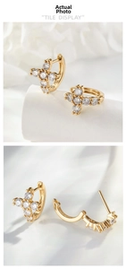 Macro view of gold cross hoop earrings with sparkling cubic zirconia on white fabric