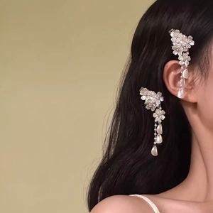 Side view detail of elegant white flower hair clips with long tassels on dark hair.