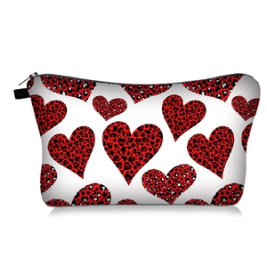 Detail of a white makeup bag with red and black leopard heart prints and black zipper