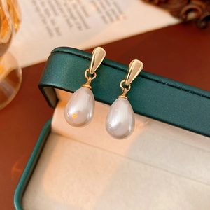 Detail of tear-drop pearl earrings on a vintage green leather jewelry box edge