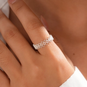 Macro shot of a silver hollow heart pattern open ring on a female finger model