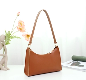 Detailed close-up of brown faux leather shoulder bag with gold zipper and minimalist design