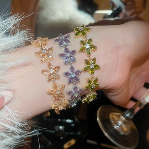 Detailed view of champagne and green floral bracelets with cubic zirconia on a wrist