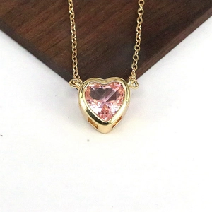 Dettaglio macro del ciondolo a cuore in zircone rosa con castone d'oro su catena