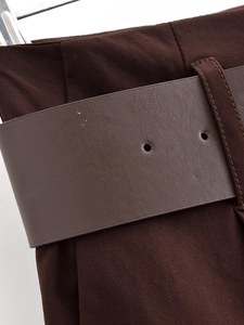 Dettaglio dei pantaloni larghi marrone scuro con cintura in ecopelle coordinata testurizzata