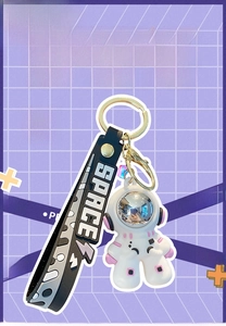 Detail of cartoon astronaut keychain with silver mask and black SPACE wrist strap