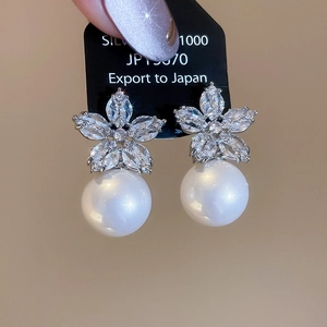 Macro shot of silver floral stud earrings featuring cubic zirconia and elegant white pearls