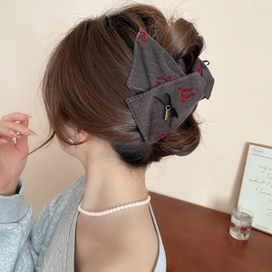 Detail of fabric bow hair claw clip with red embroidery and small ribbon pendant