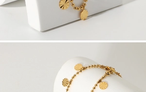 Detail of 18K gold plated beaded anklet with radiant sunburst petal disc pendants