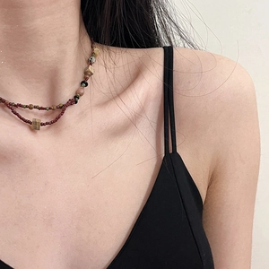 Detail of ethnic beaded double-layer necklace with red beads and wooden squares on model