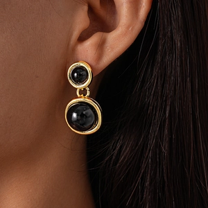 Close-up of vintage gold double-layer round earrings with black resin beads on model