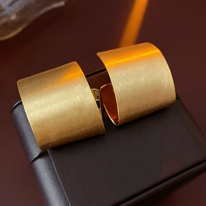 Detailed macro shot of gold-plated geometric earrings with a matte brushed metal finish