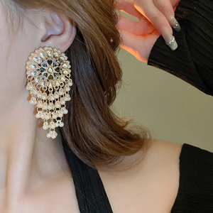 Close-up of vintage hollow drop earrings with long pearl tassels on a female model