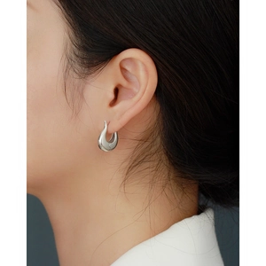 Close-up of minimalist silver drop earrings with a high-polished metallic finish on model