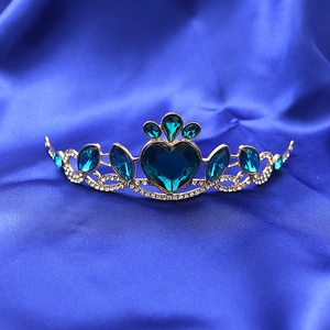 Detailed view of children princess crown featuring a heart-shaped blue crystal on blue silk