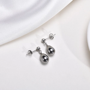 Close-up of silver teardrop earrings on white silk fabric with metallic luster