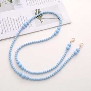 Detailed view of blue acrylic beaded crossbody chain with golden lobster clasps on magazine