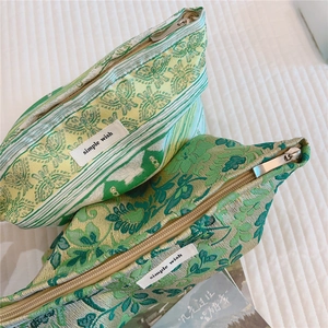 Close-up of green floral jacquard makeup bag with butterfly patterns and zipper detail