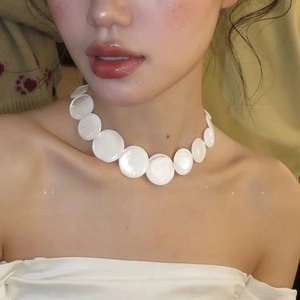Detailed close-up of white shell choker necklace featuring circular iridescent plates