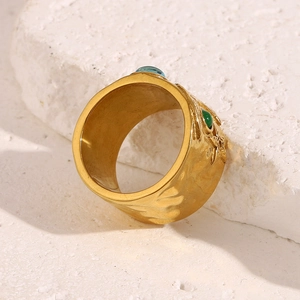 Macro d'une bague large plaquée or 18 carats avec pierres bleues sur fond de pierre