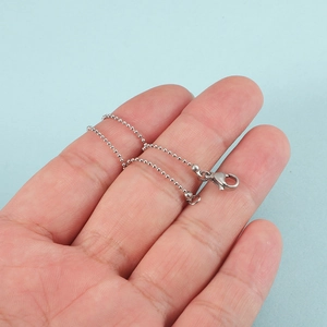 Minimalist silver bead chain bracelet for women with lobster clasp on a light blue background