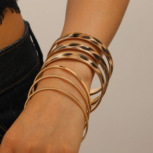 Detail van gelaagde gouden armbanden en luipaardprint armbanden om de pols van een vrouw