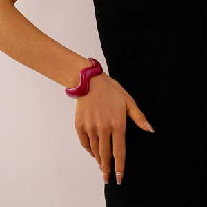 Detail view of wavy acrylic bangle featuring marble pattern in deep red resin finish
