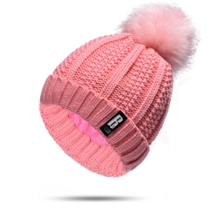 Detail of pink knitted beanie with soft pompom and warm fleece lining for winter comfort