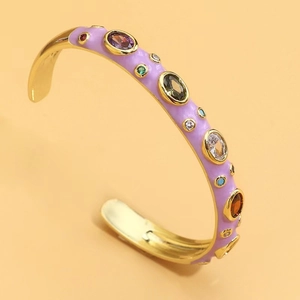 Detail of gold open bracelet with purple enamel and colorful inlaid zircon stones