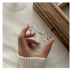 Detail shot of a minimalist S925 silver wavy textured bangle held in hand on table
