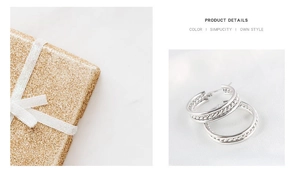 Detailed view of silver braided hoop earrings resting on white silk with a gold gift box