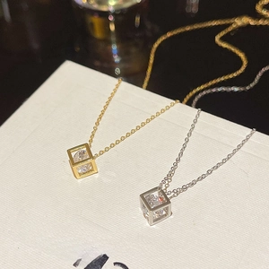 Detail view of gold and silver cube necklaces with cubic zirconia on a white texture box