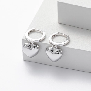 Detailed view of polished S925 sterling silver heart earrings on a minimalist pedestal