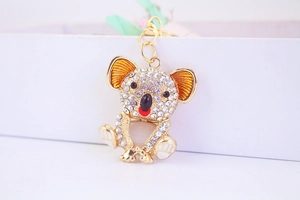 Detailed view of a gold-toned koala keychain with rhinestones and enamel in a gift box